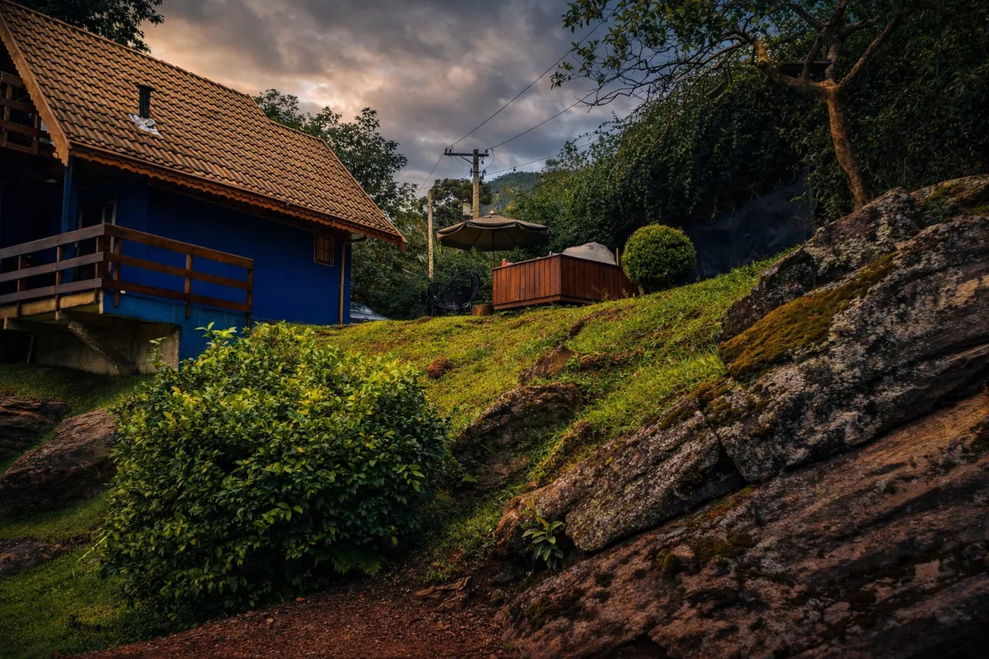 Chalé Vista da Pedra visto a partir das rochas, com a varanda e o entardecer ao fundo